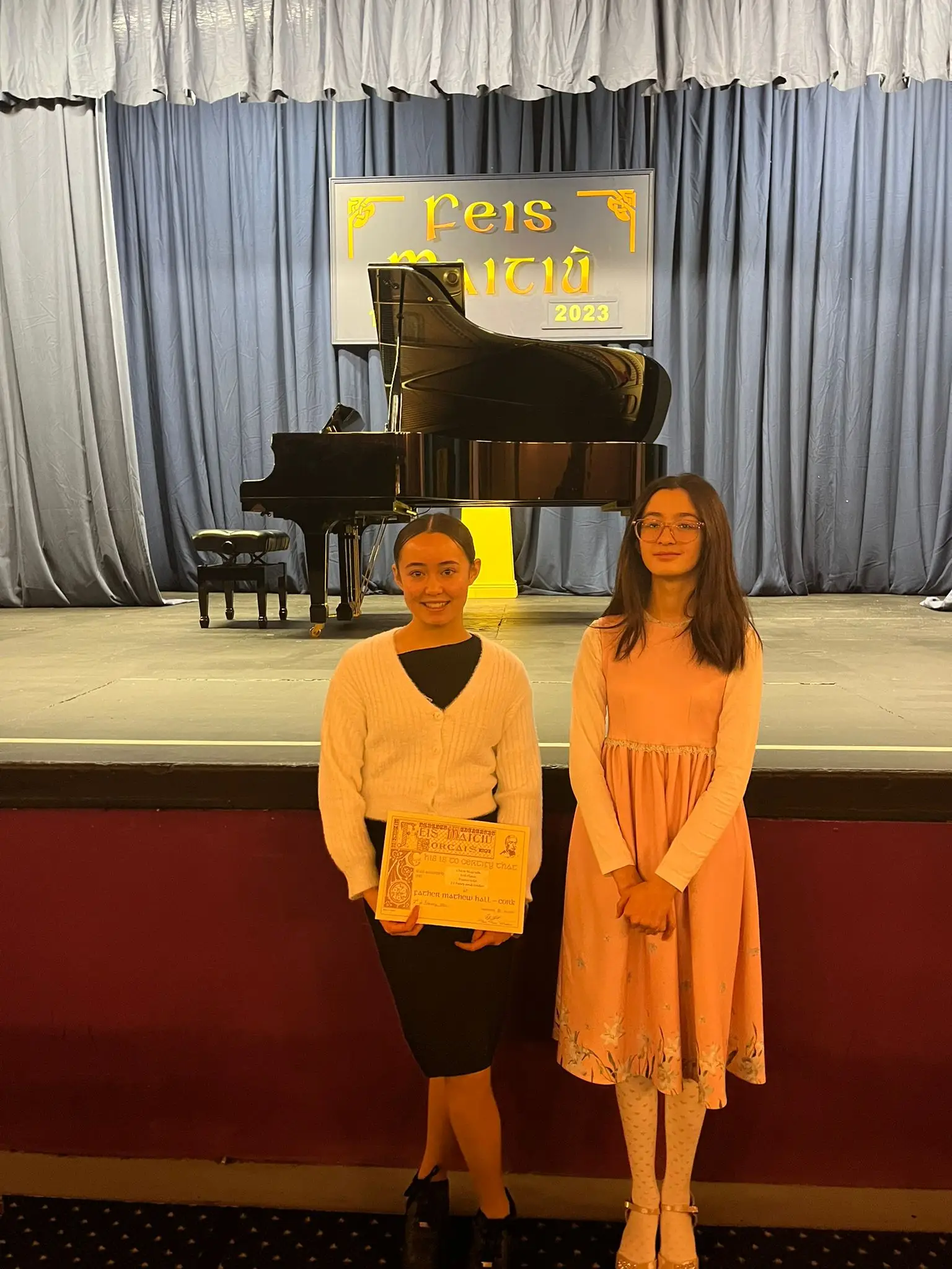 Two students in matching dresses before a duet on stage