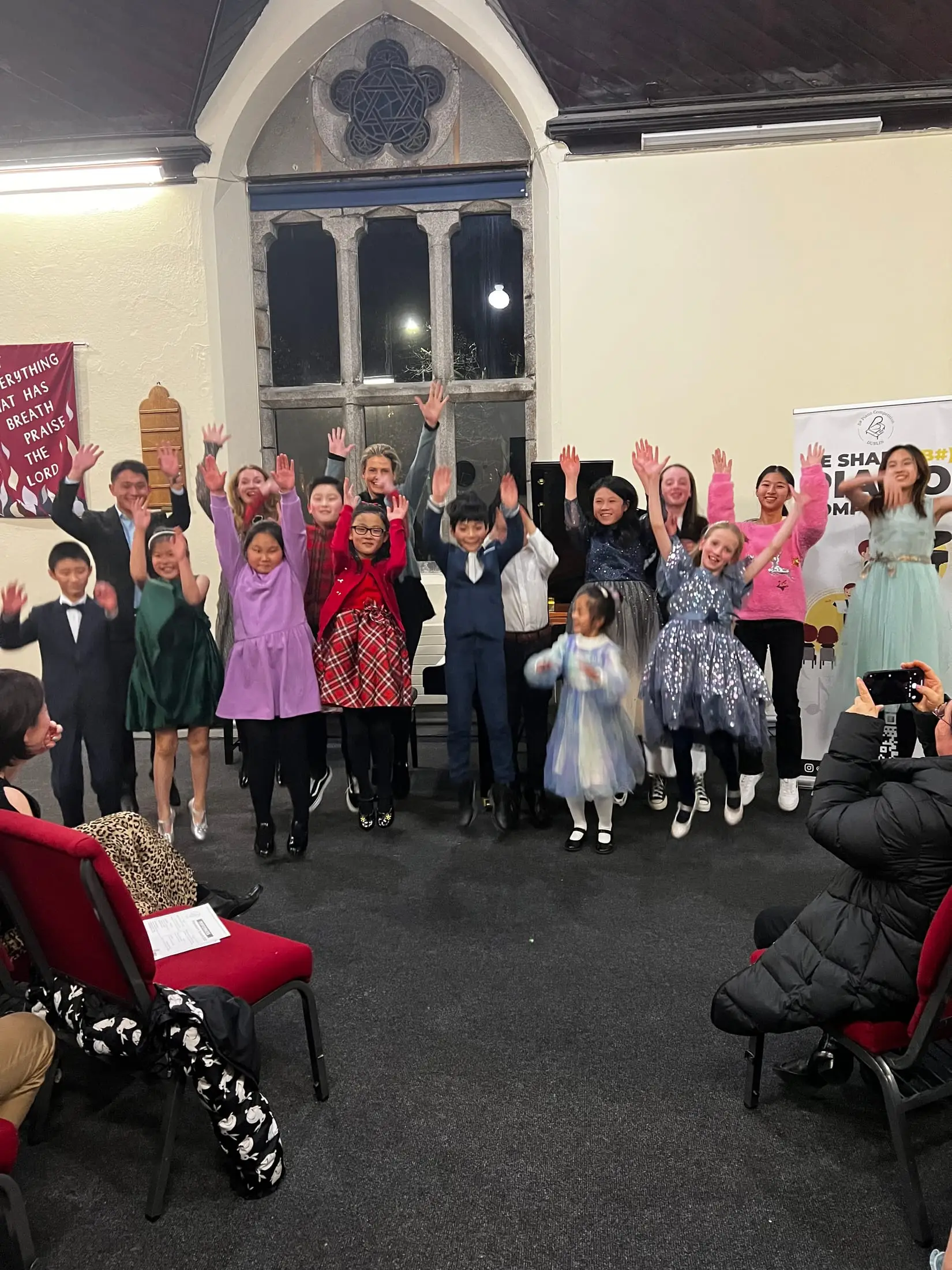 Students on stage with their arms up, celebrating at the end of a recital